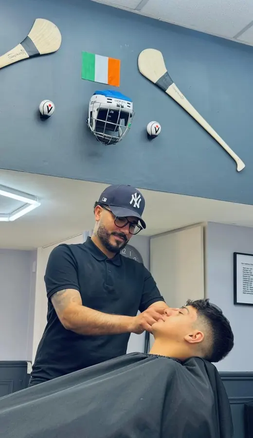 Barber shaping a beard while the client reclines
